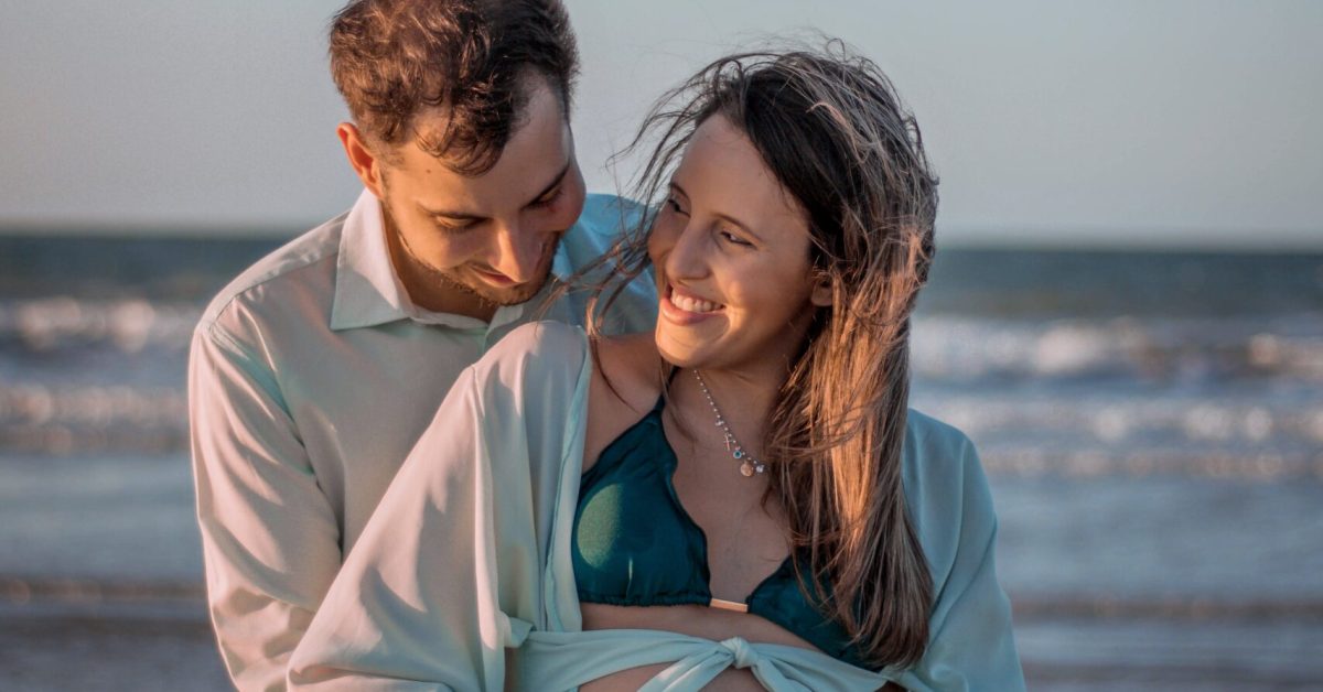 Pregnant couple on beach learning hypnobirthing